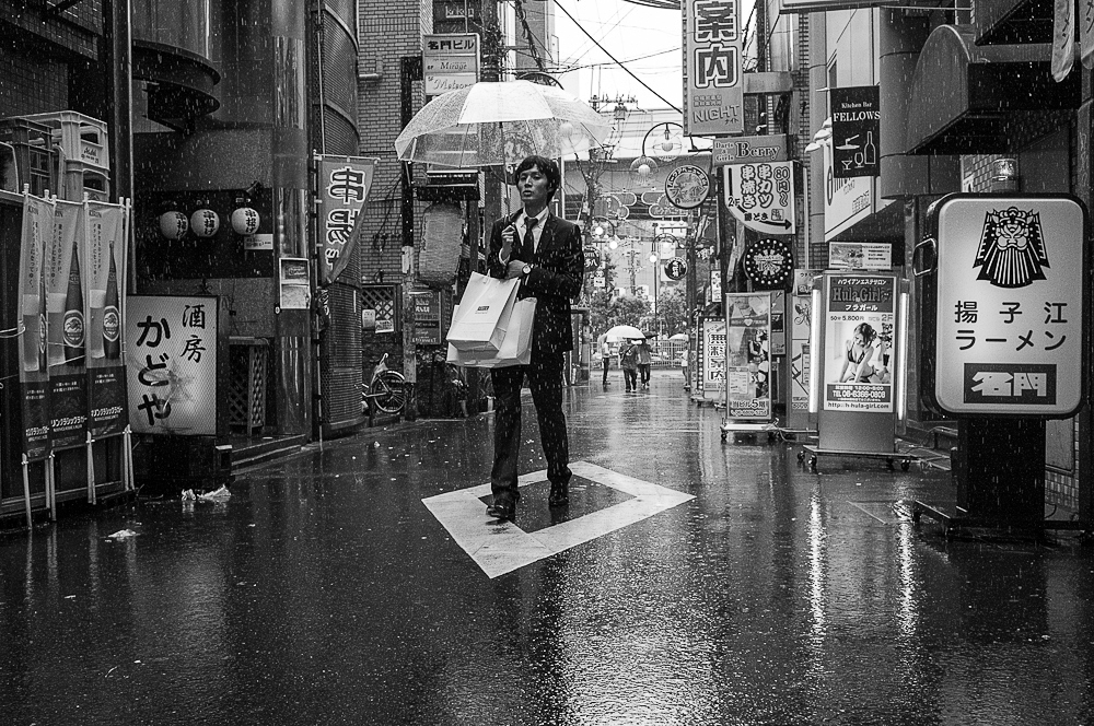 Man walking under the rain in a Japanese city