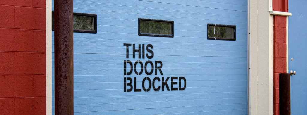 Photo of a garage door with the inscription 'this door blocked'
